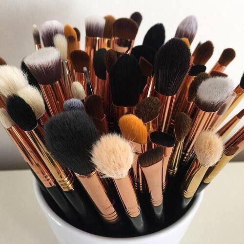 different types of makeup brushes in a  storage bucket