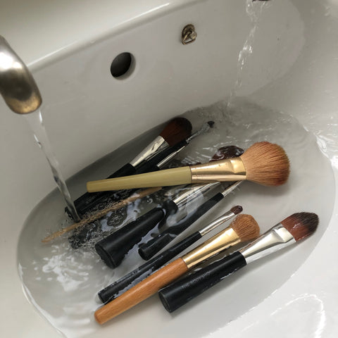 different types of makeup brushes soaked in the sink