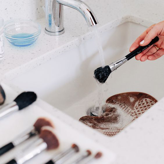 washing the makeup brushes under running water