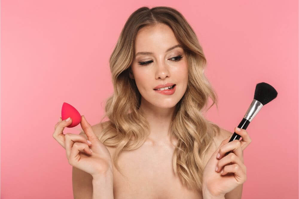 a lady handing a makeup sponge and a brush