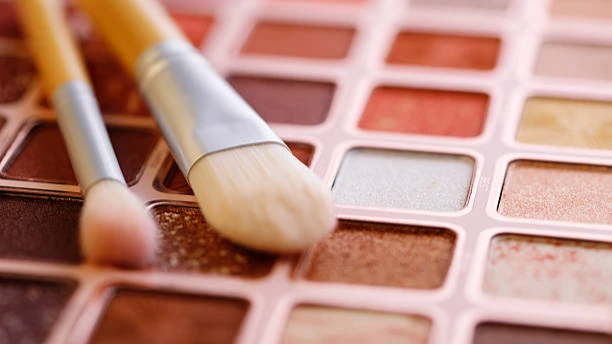Eye makeup brushes resting on a colorful eyeshadow palette.