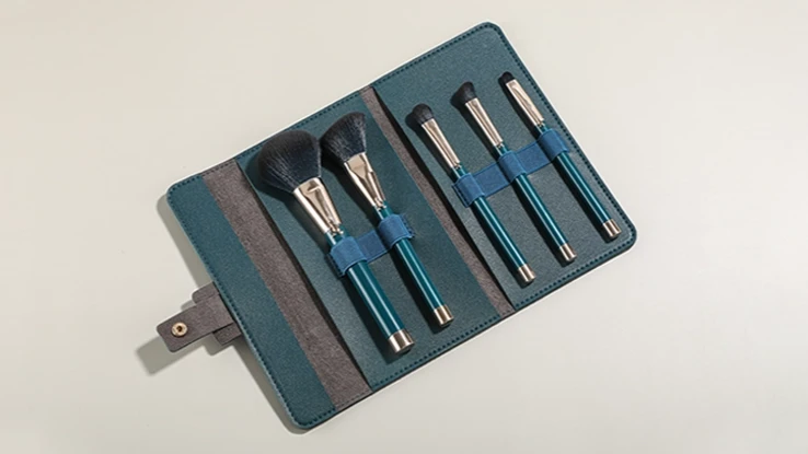 Open dark green leather makeup brush packaging case with an elastic slot organizer set.